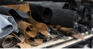 Rolls of suede leather in various colors stacked on shelves.