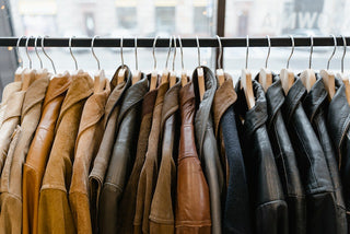 Leather jackets in various shades neatly hung on wooden hangers.
