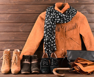 Stylish suede jacket with boots, scarf, and accessories on wooden background