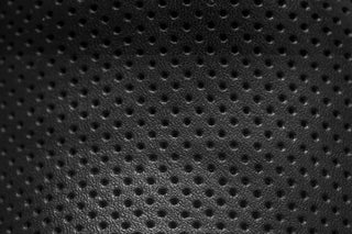 Close-up of elegant black perforated leather texture pattern.