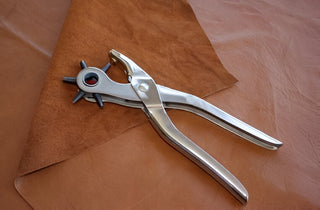 Heavy-duty leather piercing tool on brown leather sheet.